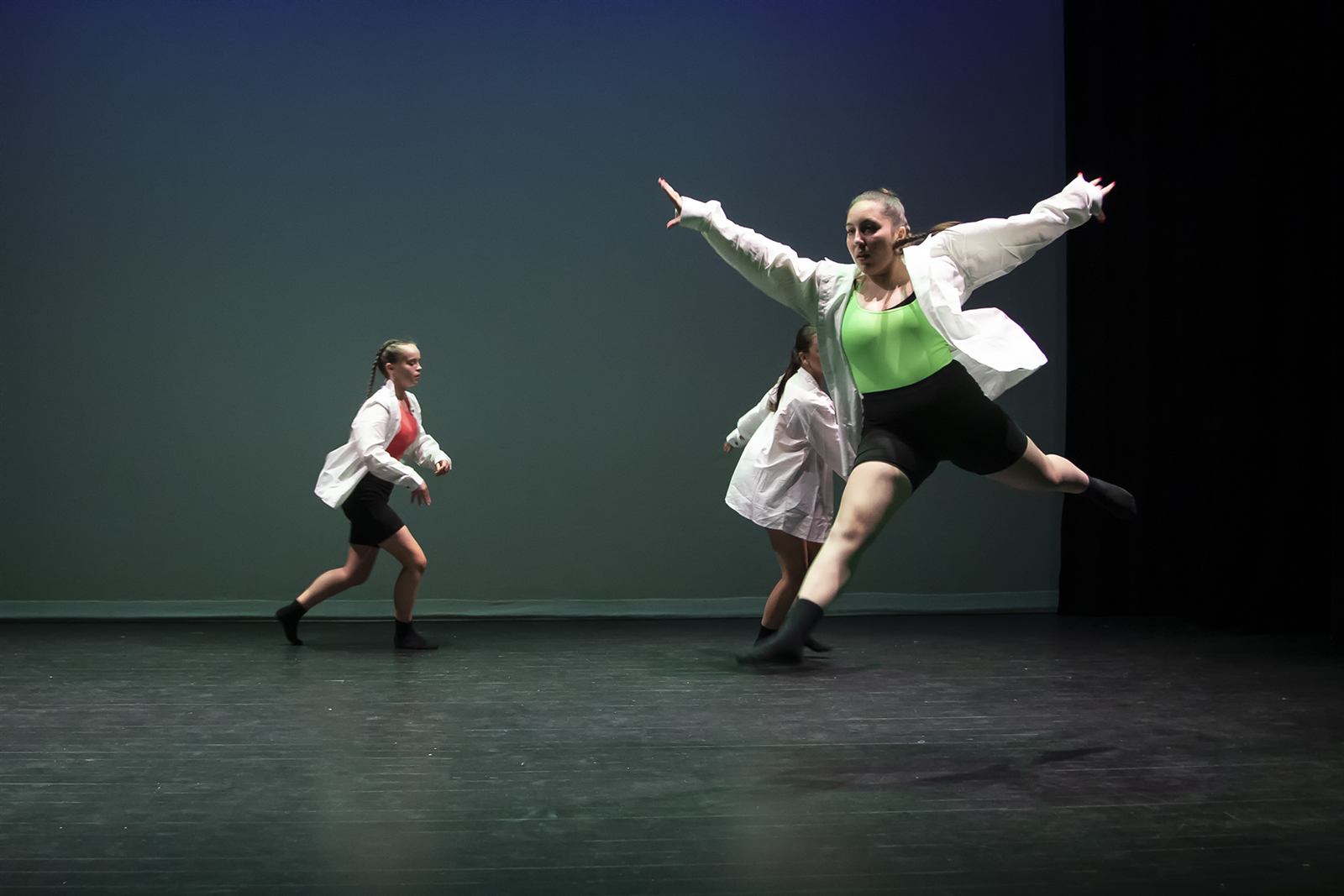 Contemporary dancers mid-leap on stage