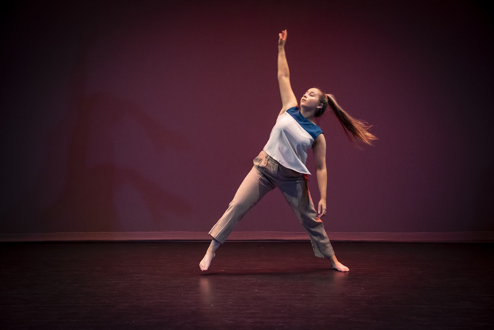 A dancer reaching upward in a spotlight on stage