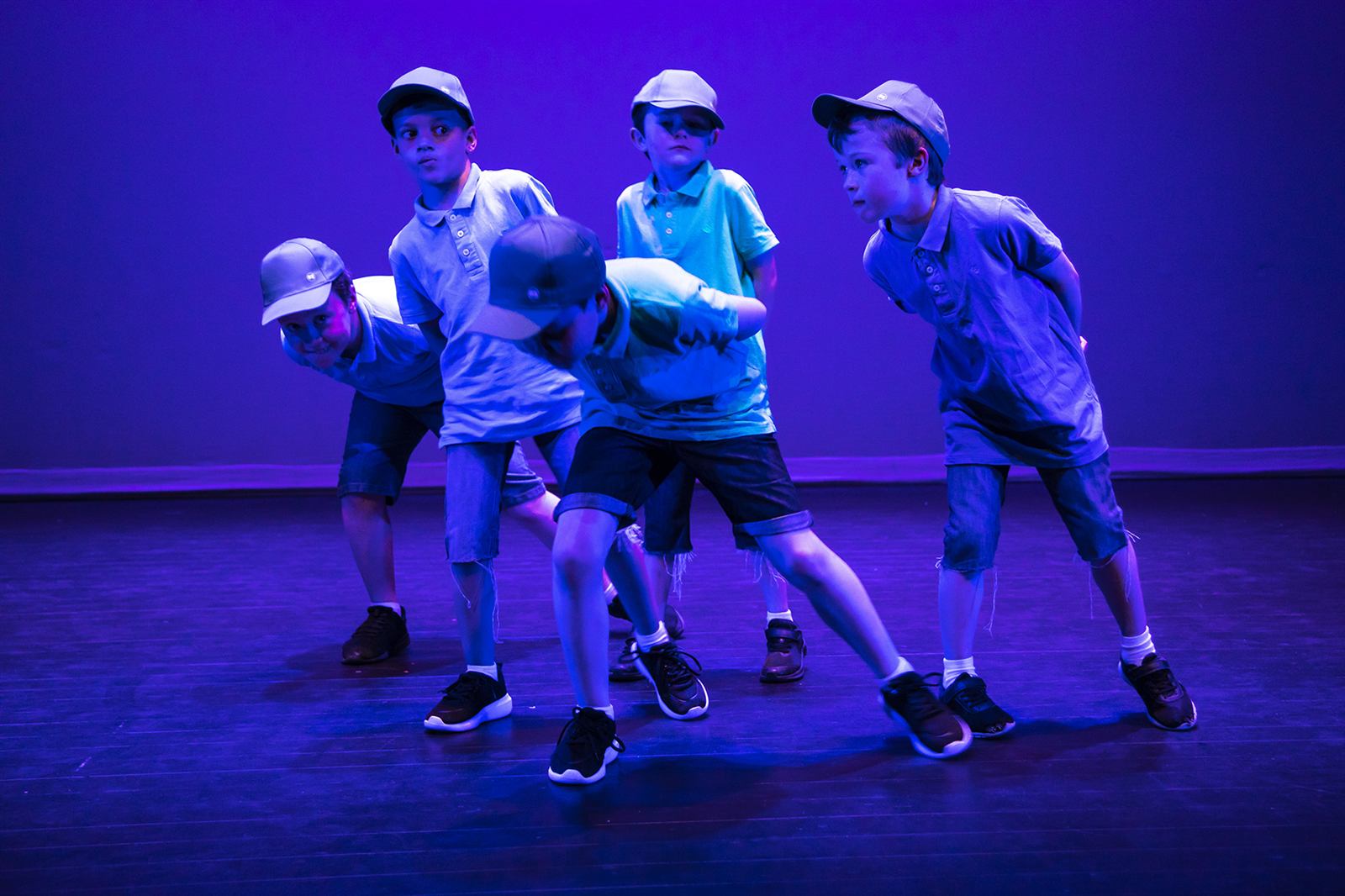 Young hip hop dancers on stage under blue lights